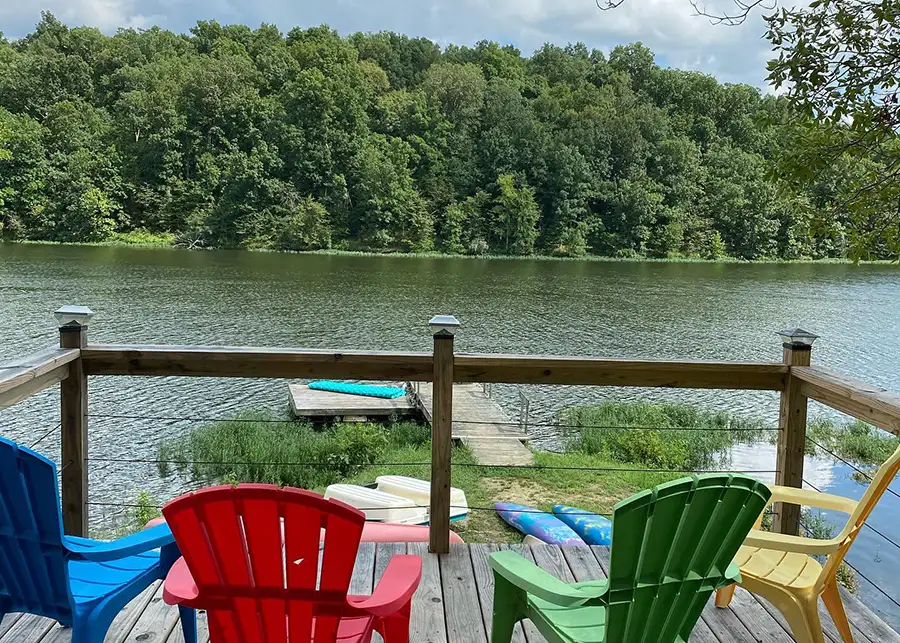 Red Roof Retreats - Jaybird Treehouse Cabin, outdoor space, dock overlooking the lake with colorful deck chairs - Lake of Egypt - Goreville, IL